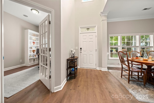 foyer entrance with crown molding and light wood-type flooring