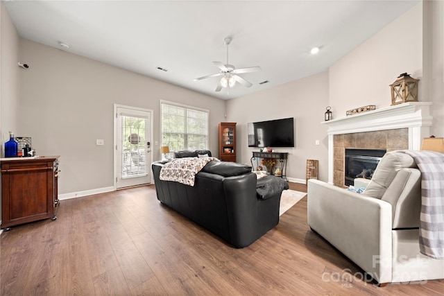 living room with a tile fireplace, ceiling fan, and hardwood / wood-style floors