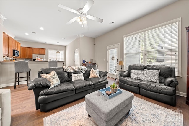 living room featuring ceiling fan, light hardwood / wood-style floors, and a wealth of natural light