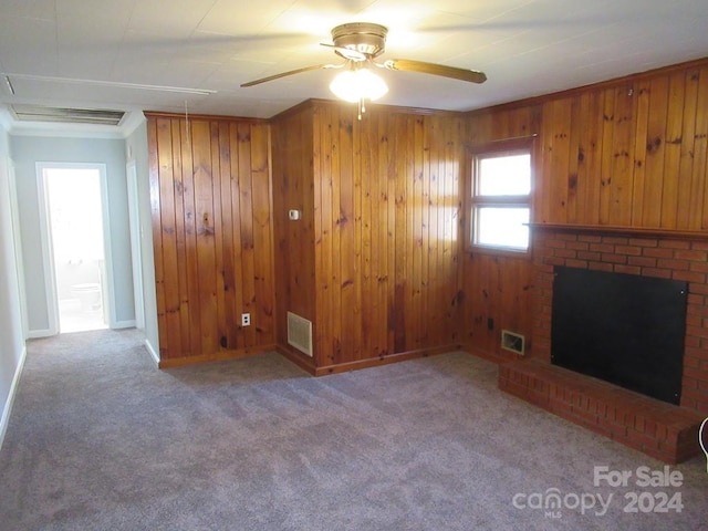 unfurnished living room featuring wood walls, ceiling fan, and light colored carpet