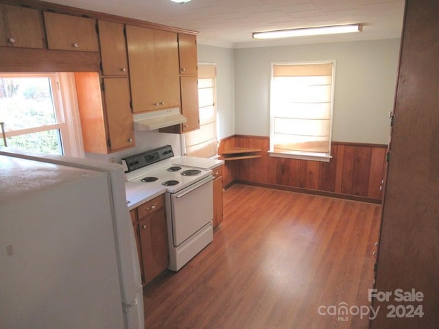 kitchen with wood walls, light hardwood / wood-style flooring, and white appliances