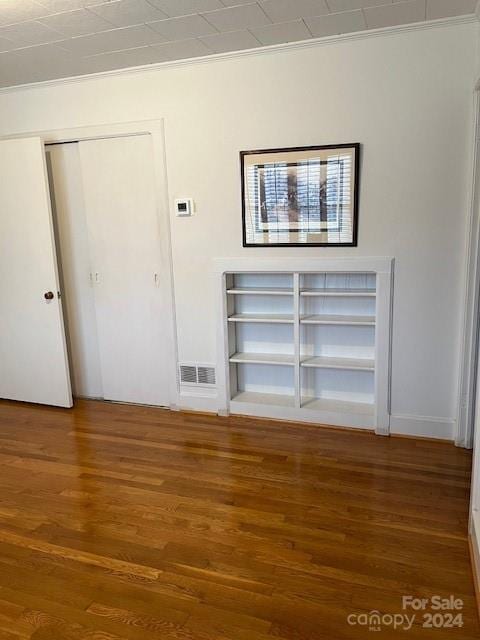 unfurnished living room featuring hardwood / wood-style flooring and ornamental molding