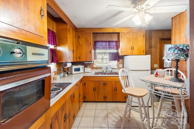 kitchen featuring ceiling fan, sink, light tile patterned floors, and white appliances