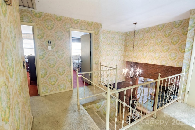 hallway featuring carpet flooring and a chandelier