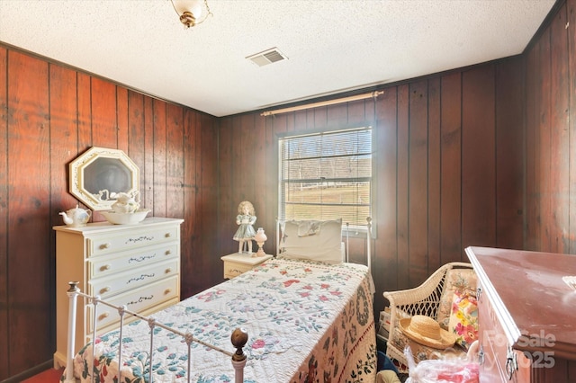 bedroom with wood walls and a textured ceiling