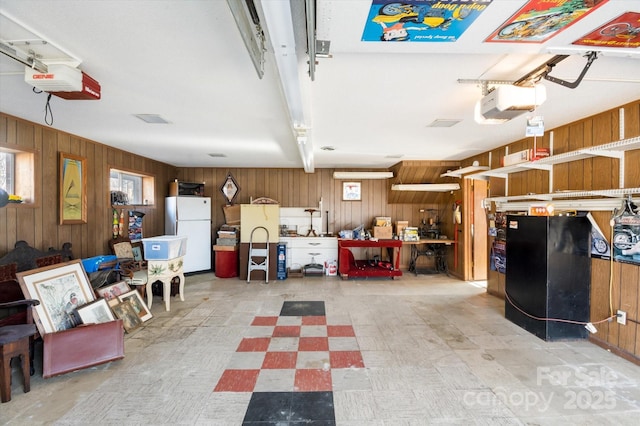 garage with white refrigerator, a garage door opener, and wood walls