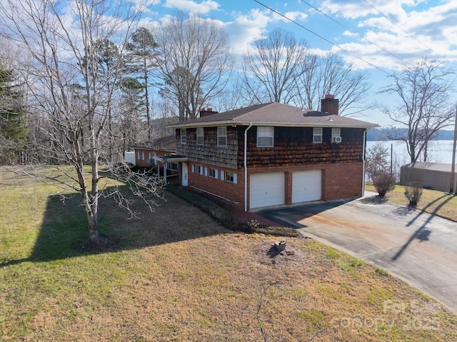 view of side of home featuring a water view, a garage, and a lawn