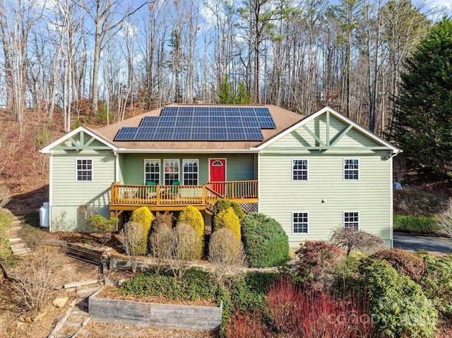 view of front of house featuring a deck, solar panels, and a shingled roof