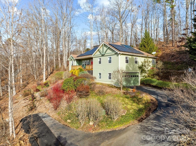 view of side of property with solar panels, driveway, and a garage