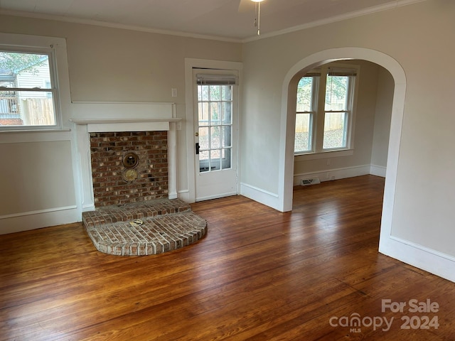 unfurnished living room with a fireplace, dark hardwood / wood-style floors, ceiling fan, and crown molding