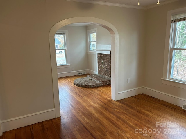 unfurnished living room with hardwood / wood-style flooring, a fireplace, and crown molding