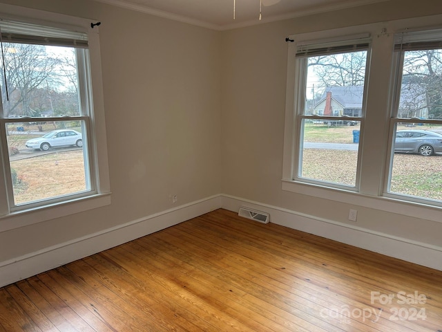 spare room with light wood-type flooring and ornamental molding