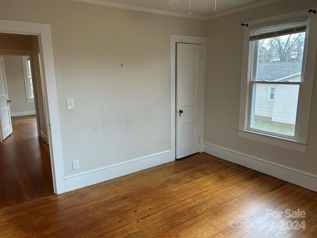 empty room with crown molding and hardwood / wood-style flooring