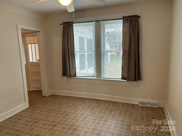 unfurnished room featuring ceiling fan and a textured ceiling