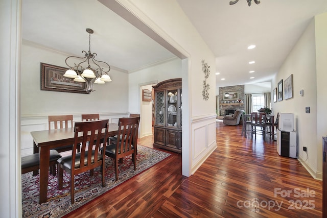 dining area featuring a notable chandelier, dark hardwood / wood-style floors, ornamental molding, and a fireplace