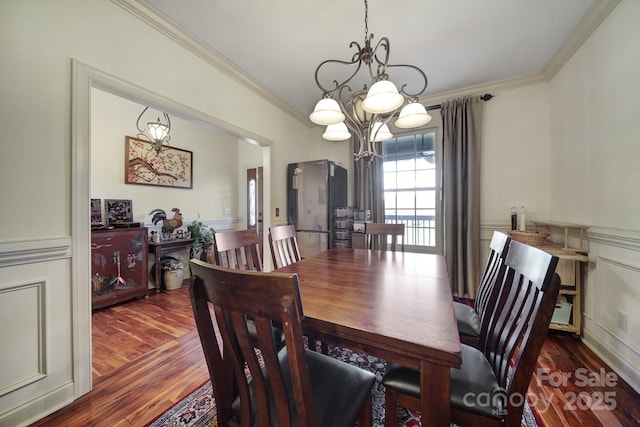 dining area featuring ornamental molding, dark wood-type flooring, and a chandelier