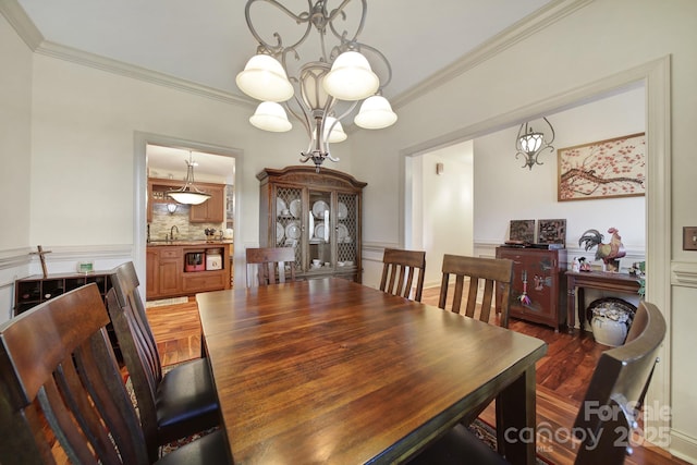 dining area featuring dark hardwood / wood-style flooring, ornamental molding, sink, and an inviting chandelier