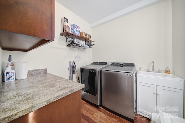 laundry room featuring washer and clothes dryer, cabinets, sink, and light hardwood / wood-style flooring