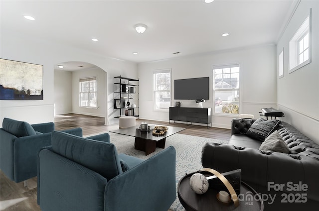 living room featuring plenty of natural light, wood-type flooring, and ornamental molding