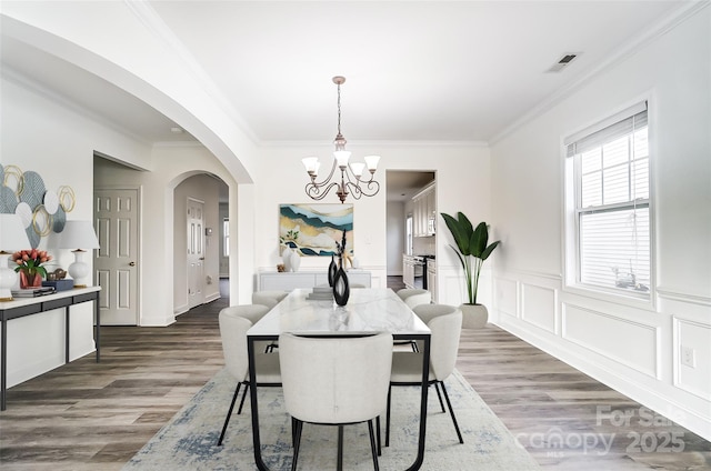 dining room featuring dark wood-type flooring, crown molding, and an inviting chandelier