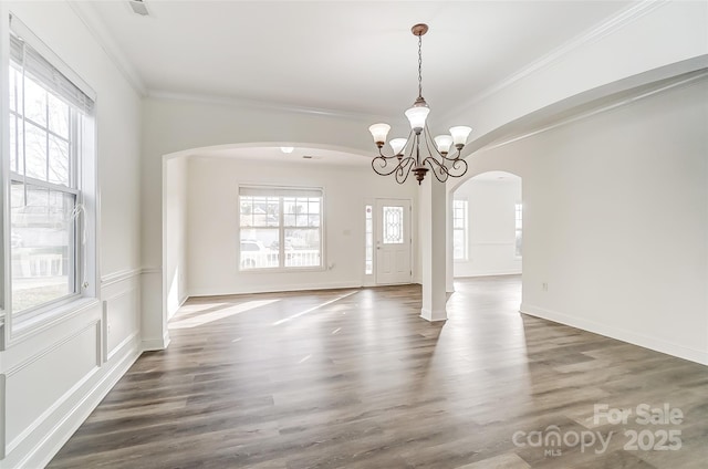 interior space featuring a wealth of natural light, dark hardwood / wood-style flooring, a notable chandelier, and ornamental molding