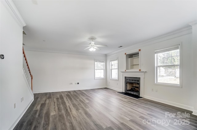 unfurnished living room featuring ceiling fan, dark hardwood / wood-style floors, crown molding, and a wealth of natural light