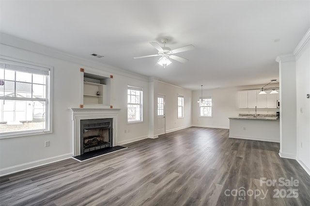 unfurnished living room with dark hardwood / wood-style flooring, ceiling fan, ornamental molding, and sink