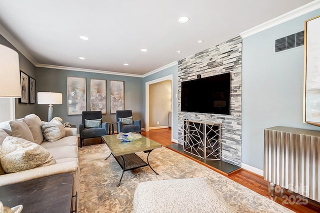 living room with a fireplace, ornamental molding, hardwood / wood-style flooring, and radiator heating unit