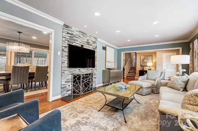 living room with a fireplace, an inviting chandelier, hardwood / wood-style flooring, and crown molding