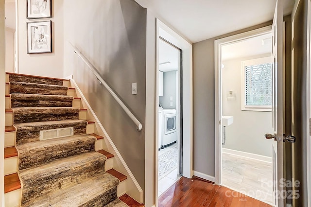 stairway with hardwood / wood-style floors and washer / clothes dryer