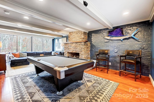 playroom with a stone fireplace, crown molding, beamed ceiling, billiards, and hardwood / wood-style flooring