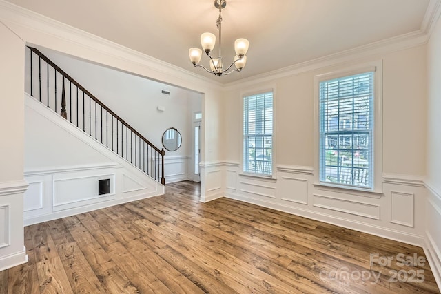 foyer with crown molding, a chandelier, and hardwood / wood-style flooring