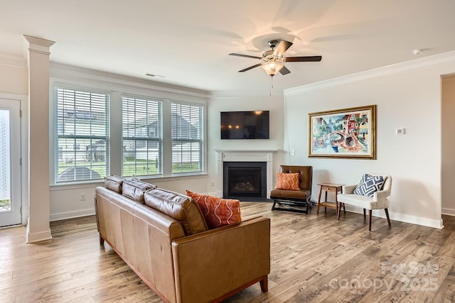 living room featuring decorative columns, light hardwood / wood-style flooring, ornamental molding, and ceiling fan