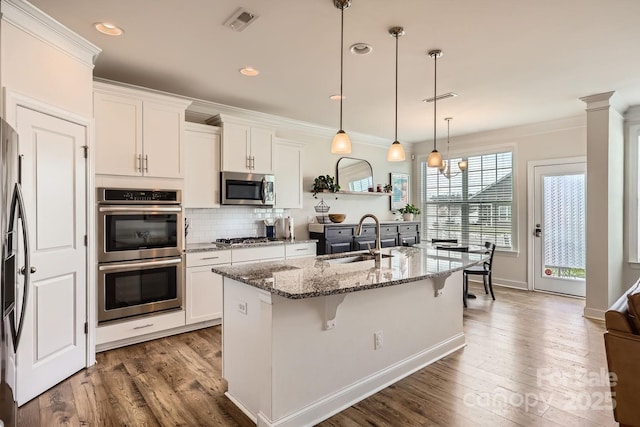 kitchen featuring an island with sink, sink, stainless steel appliances, and white cabinetry