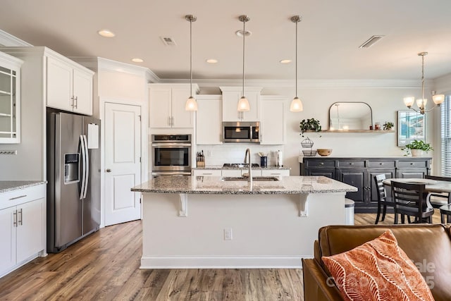 kitchen featuring a kitchen bar, sink, white cabinetry, and stainless steel appliances