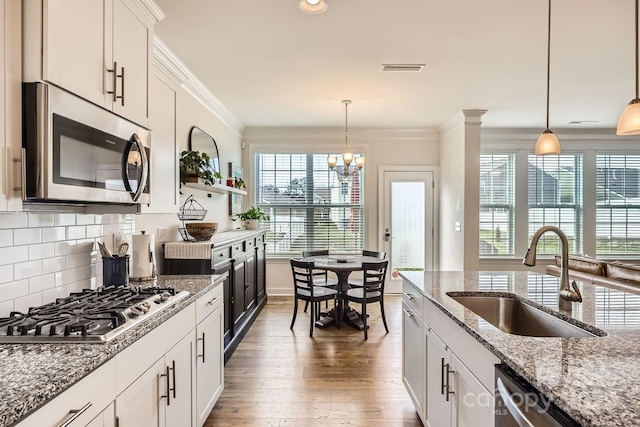 kitchen featuring pendant lighting, sink, white cabinets, and appliances with stainless steel finishes