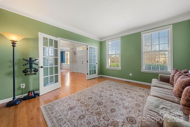 living room with ornamental molding, french doors, and light hardwood / wood-style flooring