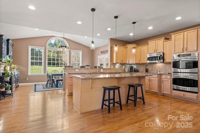 kitchen with tasteful backsplash, light stone countertops, light brown cabinets, and appliances with stainless steel finishes