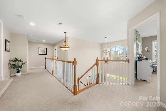 hall featuring light carpet and a notable chandelier