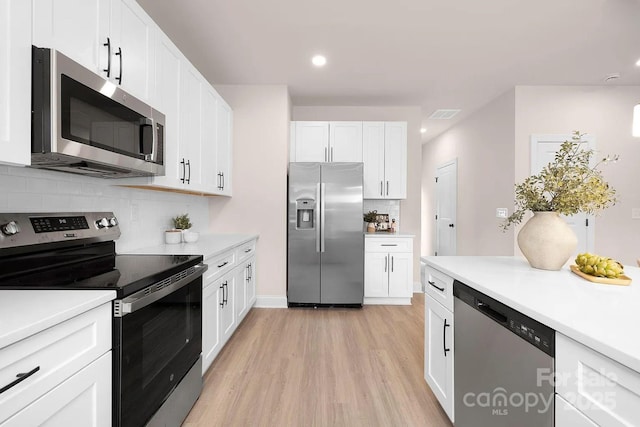 kitchen featuring decorative backsplash, appliances with stainless steel finishes, light hardwood / wood-style floors, and white cabinetry