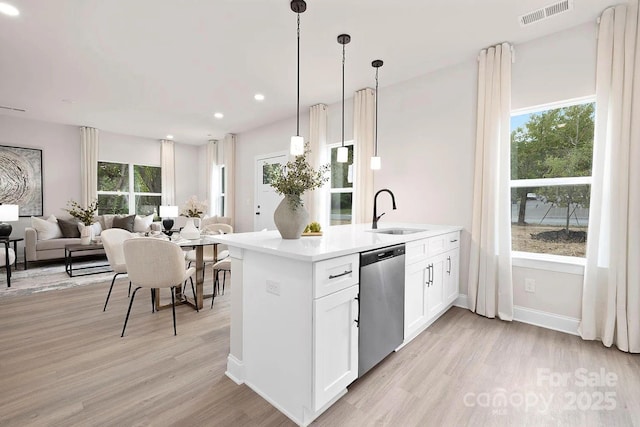 kitchen with stainless steel dishwasher, sink, light hardwood / wood-style flooring, white cabinets, and hanging light fixtures