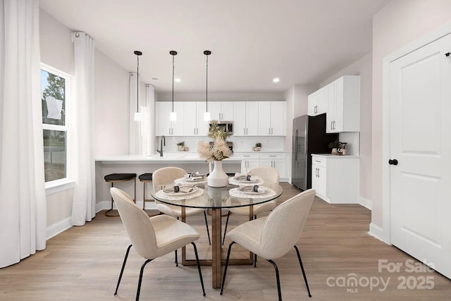 dining space with light hardwood / wood-style flooring, plenty of natural light, and sink