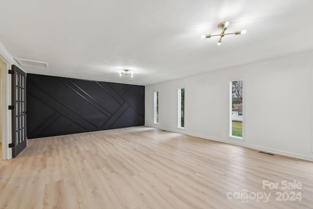 spare room with an inviting chandelier and light hardwood / wood-style flooring