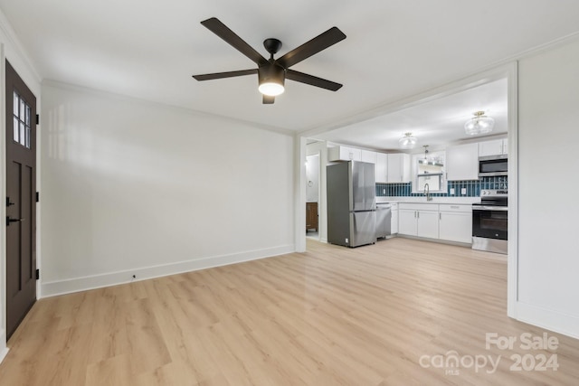 unfurnished living room featuring ceiling fan, light wood-type flooring, and ornamental molding