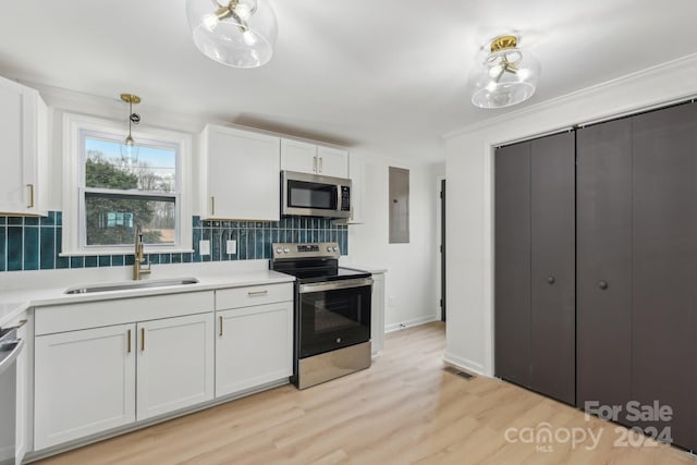 kitchen with sink, hanging light fixtures, light hardwood / wood-style floors, white cabinets, and appliances with stainless steel finishes