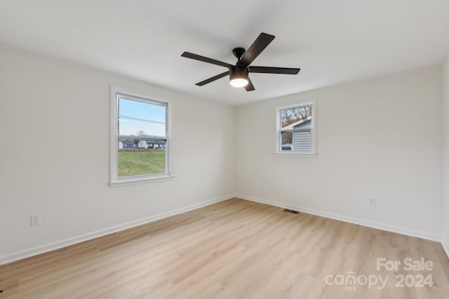 spare room featuring ceiling fan, a healthy amount of sunlight, and light hardwood / wood-style floors