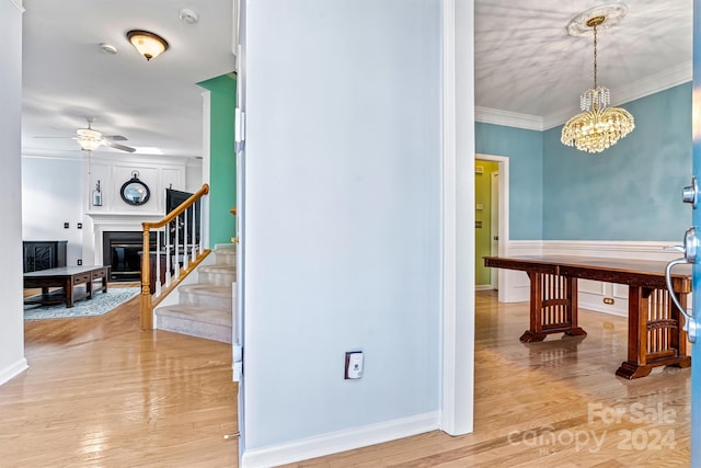 hallway featuring light hardwood / wood-style floors, crown molding, and an inviting chandelier