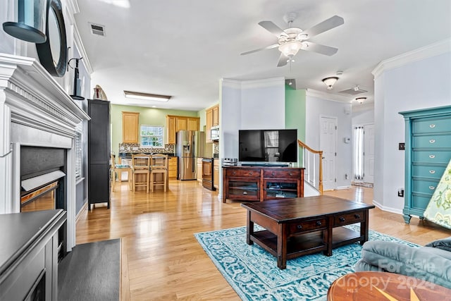 living room featuring ceiling fan, light wood-type flooring, and ornamental molding