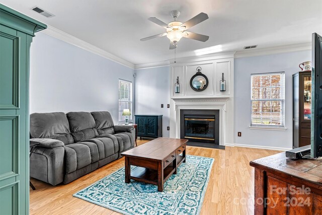 living room with ceiling fan, ornamental molding, and light hardwood / wood-style flooring