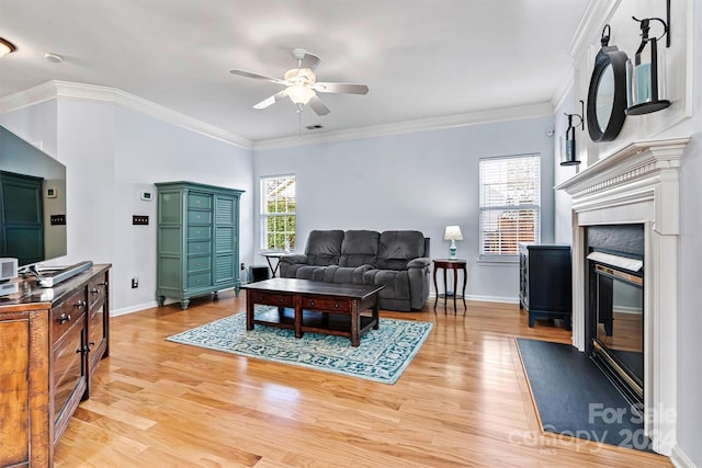 living room featuring light hardwood / wood-style flooring, ceiling fan, crown molding, and a premium fireplace